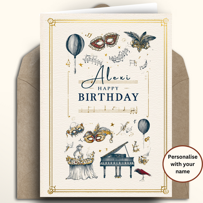A customisable birthday card with a masquerade theme, shown standing upright in front of a brown envelope. The cream card features gold border details, blue and gold illustrations of masks, a grand piano, and hot air balloons, with the text 'Alexi Happy BIRTHDAY'.
