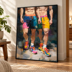 Two of a Kind gay couple print in a black frame leaning on a sunlit wood floor beside a side table and plant, two men in colourful shorts and trainers