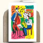 A greeting card featuring a colorful jazz musician illustration, displayed upright on top of a brown kraft envelope against a light beige background.