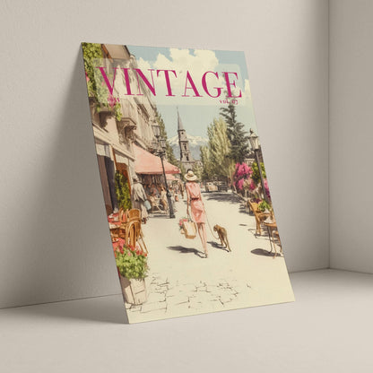 A vintage-style illustrated magazine or book cover titled "VINTAGE" leans against a light gray wall on a matching floor. The cover art shows a sunlit street scene with people, dogs, storefronts, and trees, rendered in soft pastel tones.