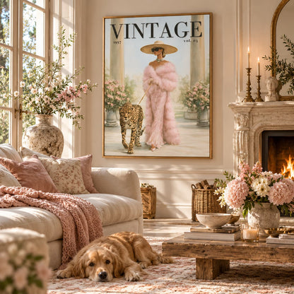 A large framed vintage-style wall art print hangs above a sofa in a beautifully styled living room. The artwork shows a woman in a pink fur outfit walking a leopard, with the word VINTAGE at the top.
