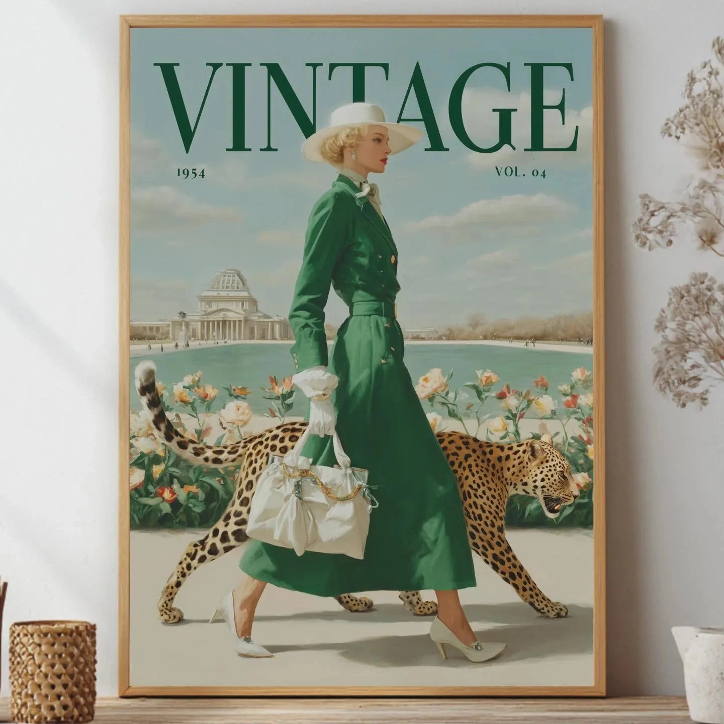 A framed vintage-style poster or print leaning on a shelf, showing a woman in a green dress walking with a leopard, with large 'VINTAGE' text at the top. The room setting includes dried flowers and small decor objects on both sides.