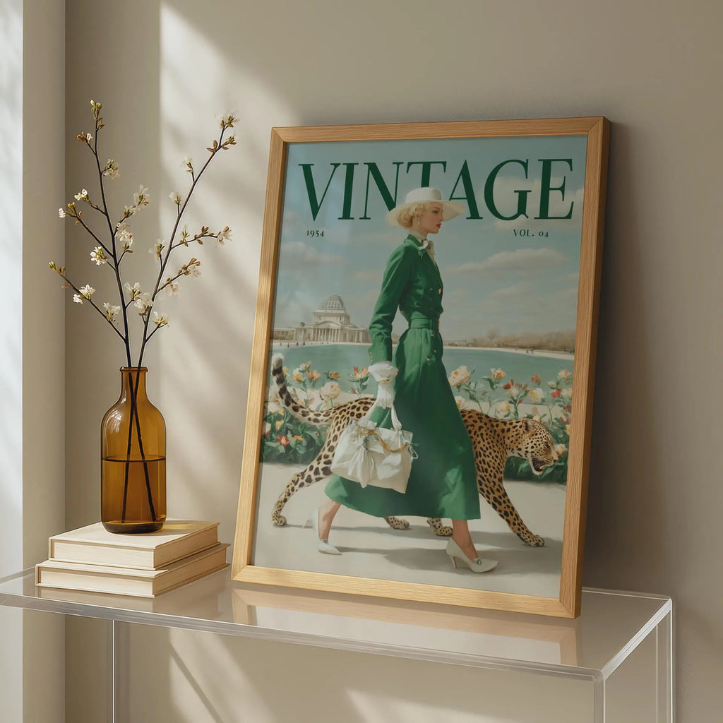 A framed vintage-style magazine cover print leaning on a glass table in a sunlit room. The cover shows the word VINTAGE prominently at the top and an illustrated woman in a green dress walking with two cheetahs.