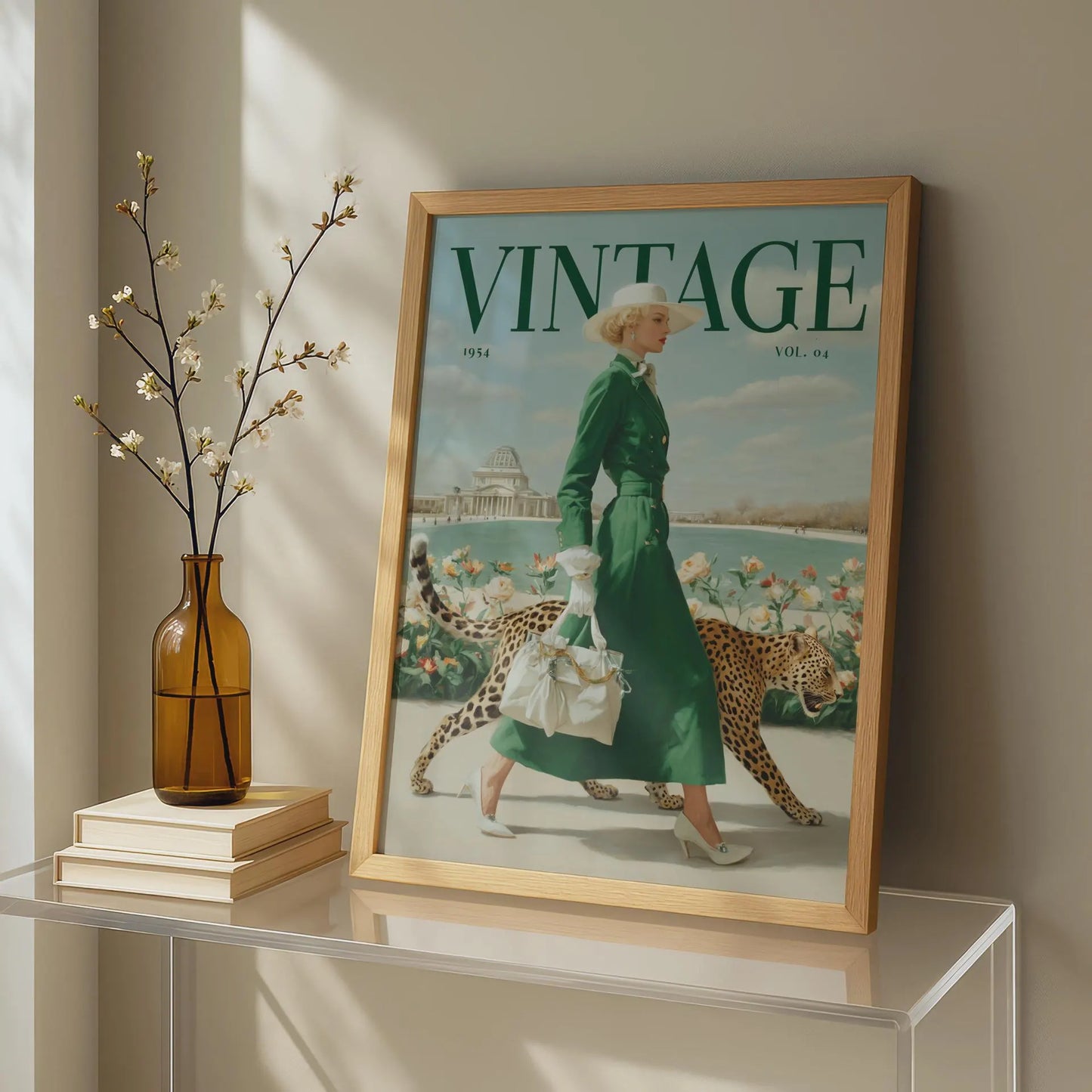 A framed vintage-style magazine cover print leaning on a glass table in a sunlit room. The cover shows the word VINTAGE prominently at the top and an illustrated woman in a green dress walking with two cheetahs.