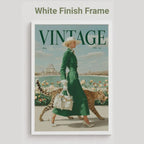 A vintage-style framed poster featuring a woman in a green dress walking with two cheetahs, with the word VINTAGE prominently printed at the top. The frame is white, and the image is shown against a light gray background with the text 'White Finish Frame' above it.