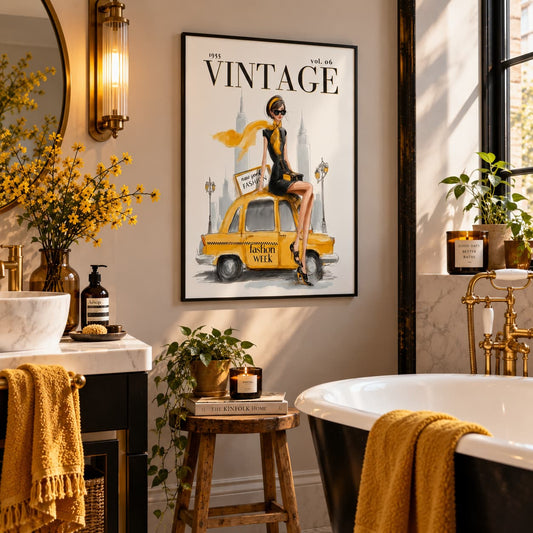 A framed vintage-style wall art print hangs in a styled bathroom. The print features a woman sitting on a yellow taxi with the words “Vintage” and “Lesley Milk” visible.