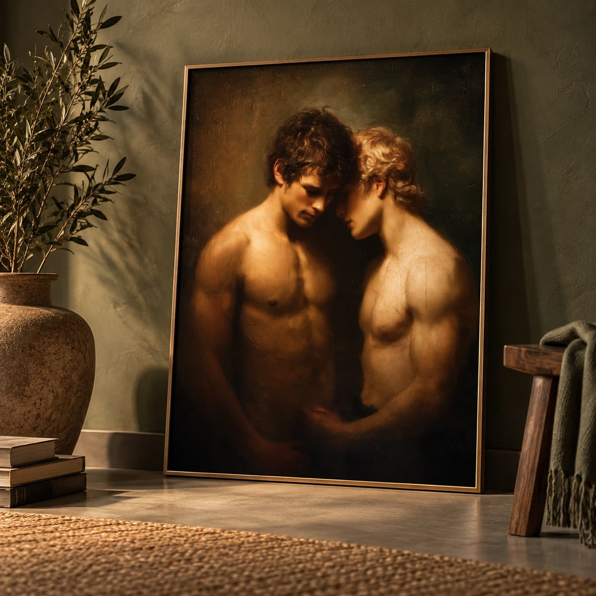 A framed classical-style painting leaning against a textured wall in a styled interior. The artwork depicts two shirtless men embracing closely, rendered in warm sepia and brown tones.