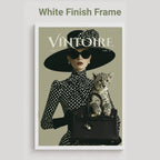 A framed art print featuring a vintage-style fashion magazine cover with the title 'VINTOIRE'. The cover shows a woman in a black and white polka dot outfit with a wide-brimmed black hat, sunglasses, and a black handbag holding a spotted kitten.