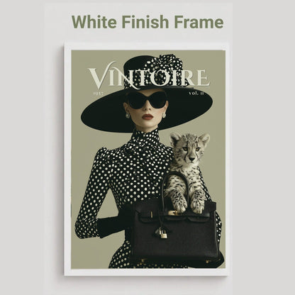 A framed art print featuring a vintage-style fashion magazine cover with the title 'VINTOIRE'. The cover shows a woman in a black and white polka dot outfit with a wide-brimmed black hat, sunglasses, and a black handbag holding a spotted kitten.