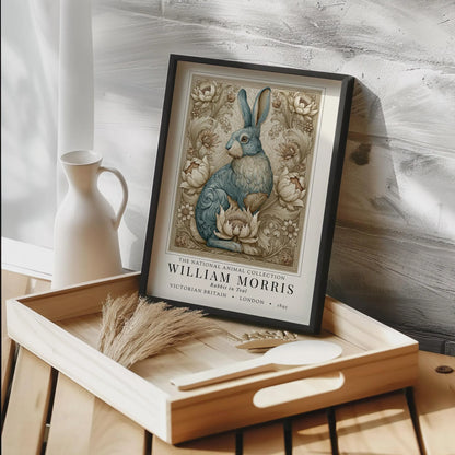 Framed artwork of a rabbit on a wooden tray with decorative items. William Morris inspired exhibition poster.