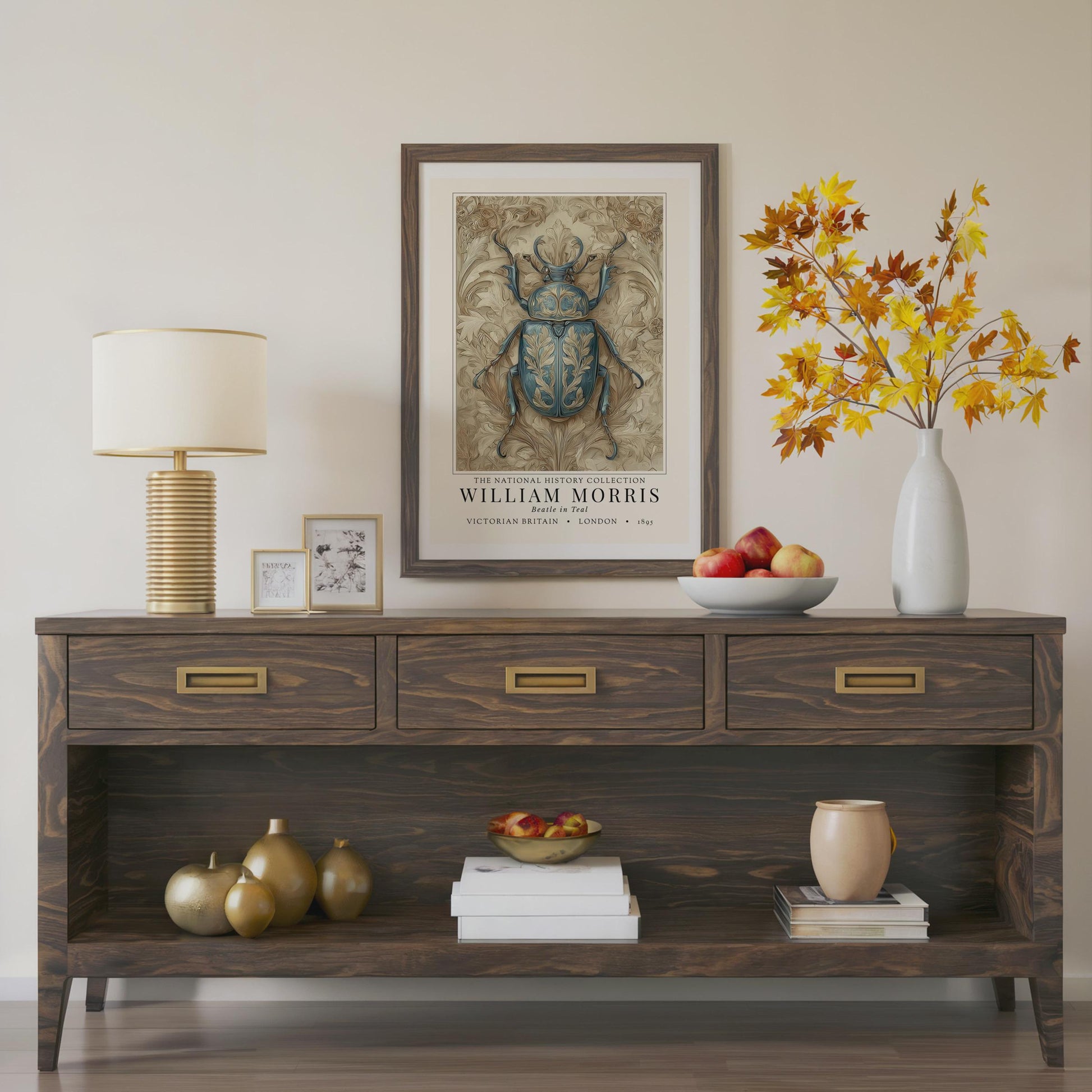 Wooden console table with decorative items including a lamp, framed artwork, and vases.William Morris teal beetle exhibition print in a black frame on a cream painted wall, victorian insect art poster