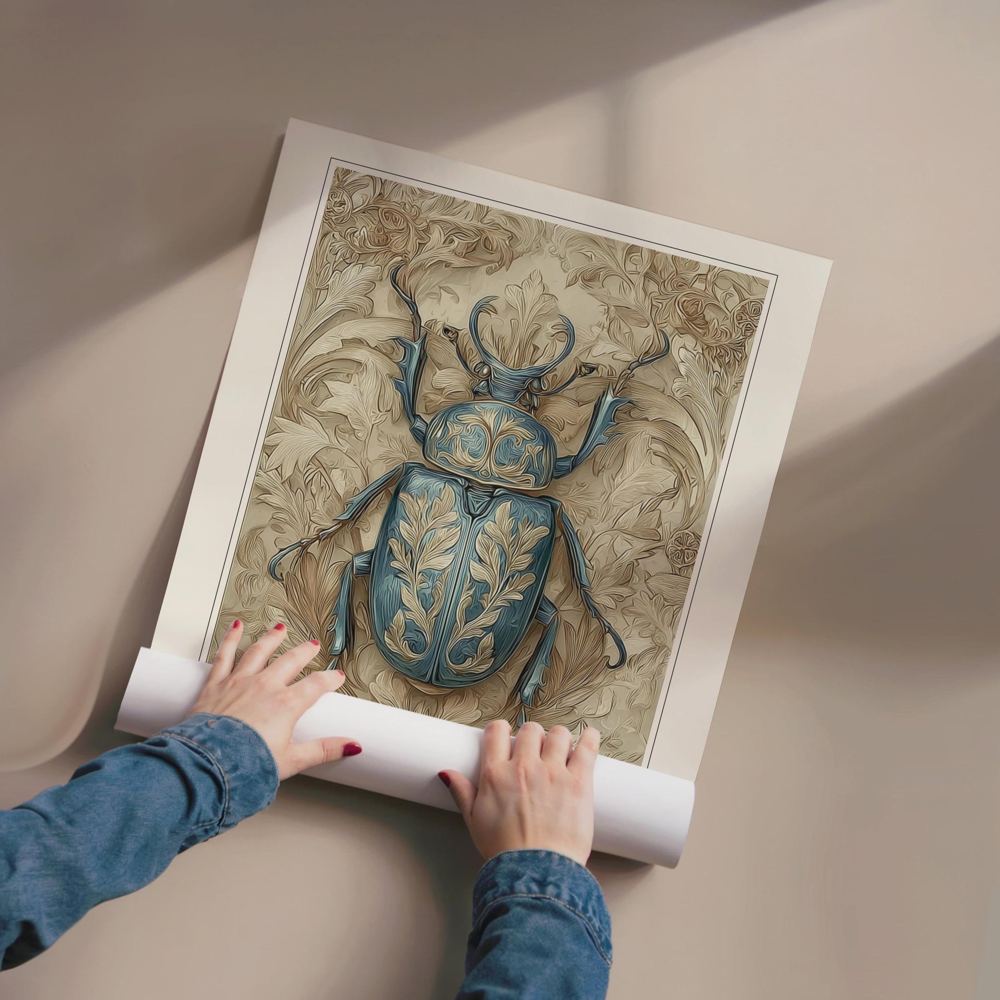 Person unrolling a large print of a detailed beetle illustration on a beige surface.William Morris teal beetle exhibition print in a black frame on a cream painted wall, victorian insect art poster