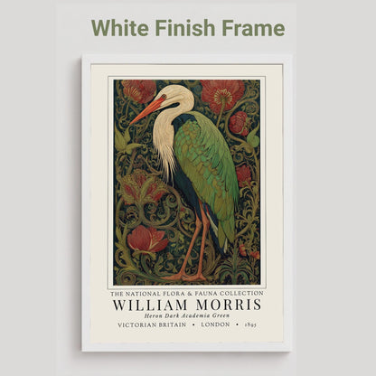 Black framed artwork of a William Morris inspired heron exhibition poster in a jewel-toned palette of forest green, antique crimson and old gold, featuring a grey heron amid ornate pimpernel blooms and curling vines — Victorian Arts and Crafts style, framed print.