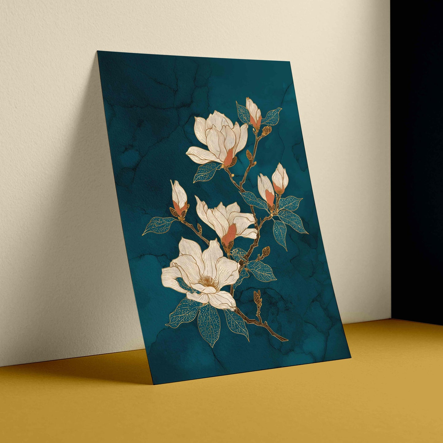 A vertical art print featuring white magnolia flowers with teal leaves on a dark teal marbled background, shown leaning against a beige wall on a mustard yellow surface.
