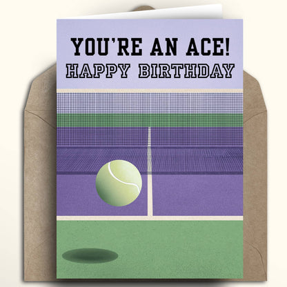 A tennis-themed birthday card with a kraft envelope behind it. The card reads 'YOU'RE AN ACE! HAPPY BIRTHDAY' above an illustrated purple and green tennis court with a tennis ball.