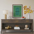 Wooden console table with decorative items including a lamp, framed picture, and vase.Framed artwork of a tennis court in miniature from above 