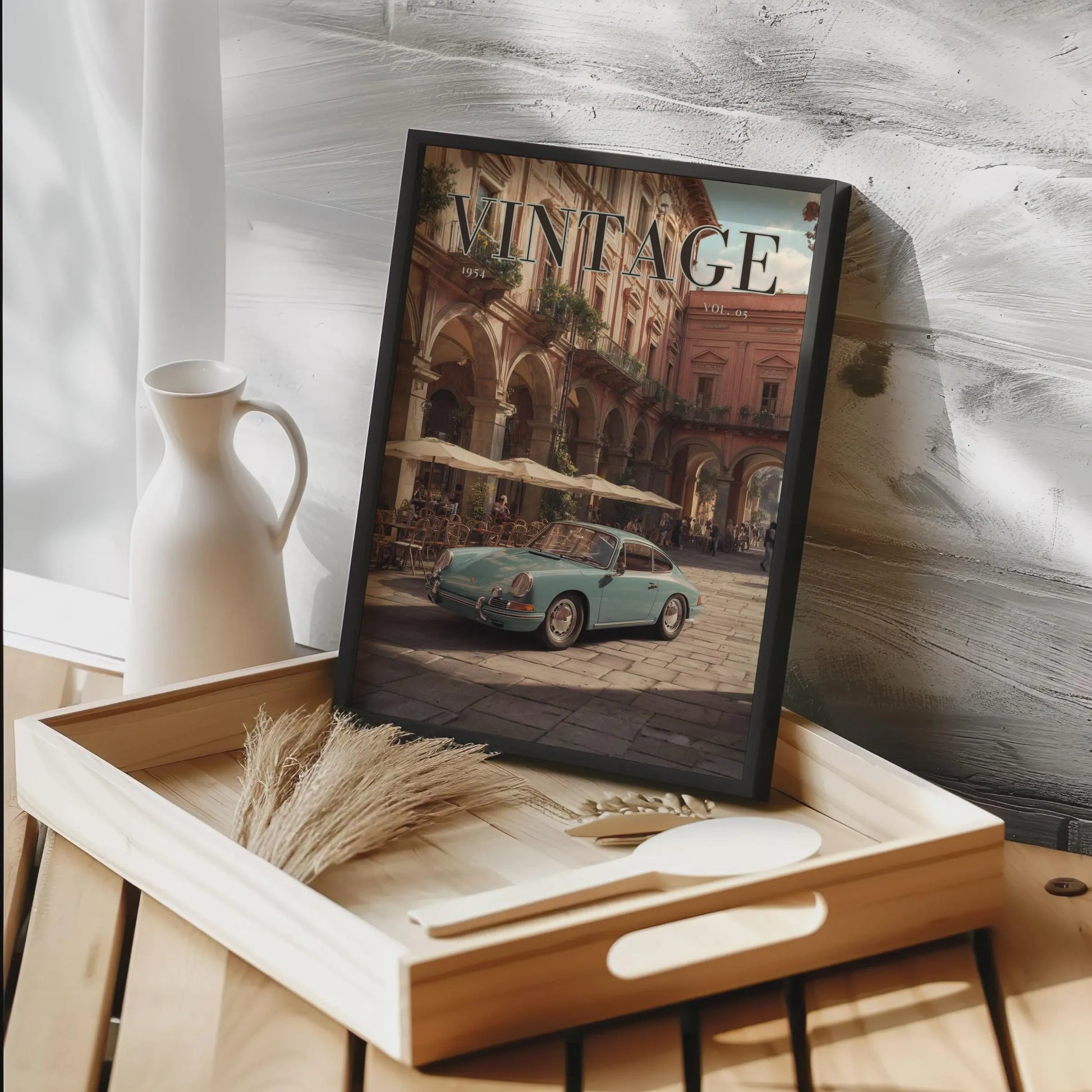 Framed vintage-style poster of a car on a wooden tray with decorative items.Vintage 1950s Porsche 911 classic car poster in a black frame on a white living room wall